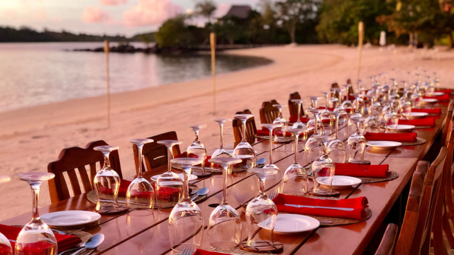 Long dining table with chairs decorated for a beach event at Turtle Island Resort