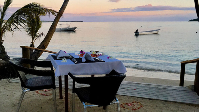 Beachfront dining area with a table set for two at Coconut Beach Resort, Tavewa Island, Fiji.