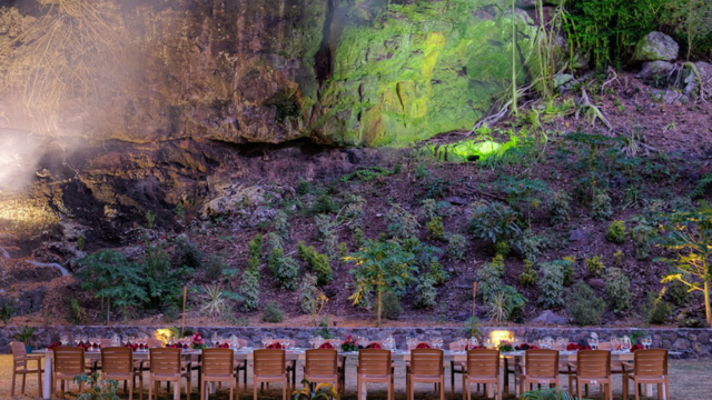 Table and chairs arranged on the beach near a cliff for a special event at Turtle Island Resort
